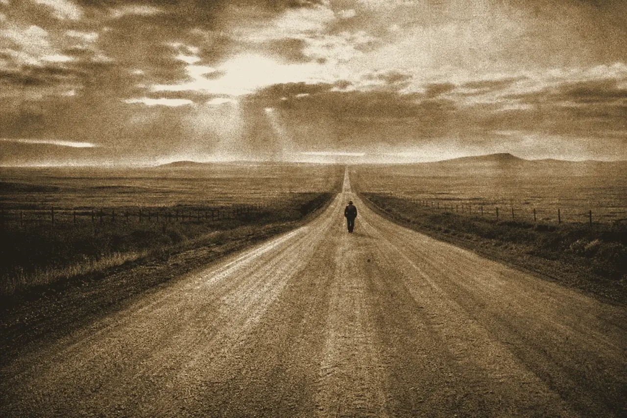 A lone figure on a long open highway at dawn under a vast prairie horizon.